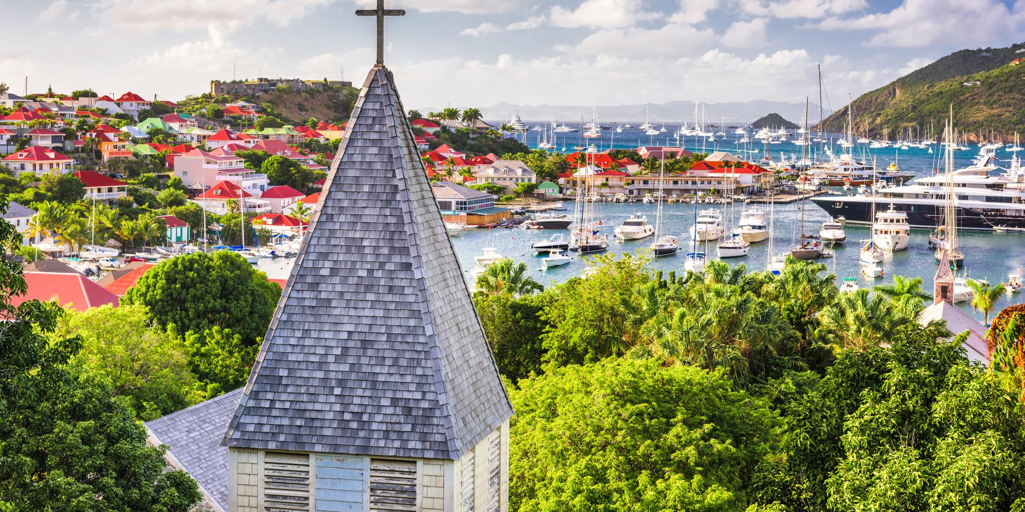 A beautiful view of a Caribbean town and ship at bay from behind Saint Barthelemy's Anglican Church on Saint Barthelemy.