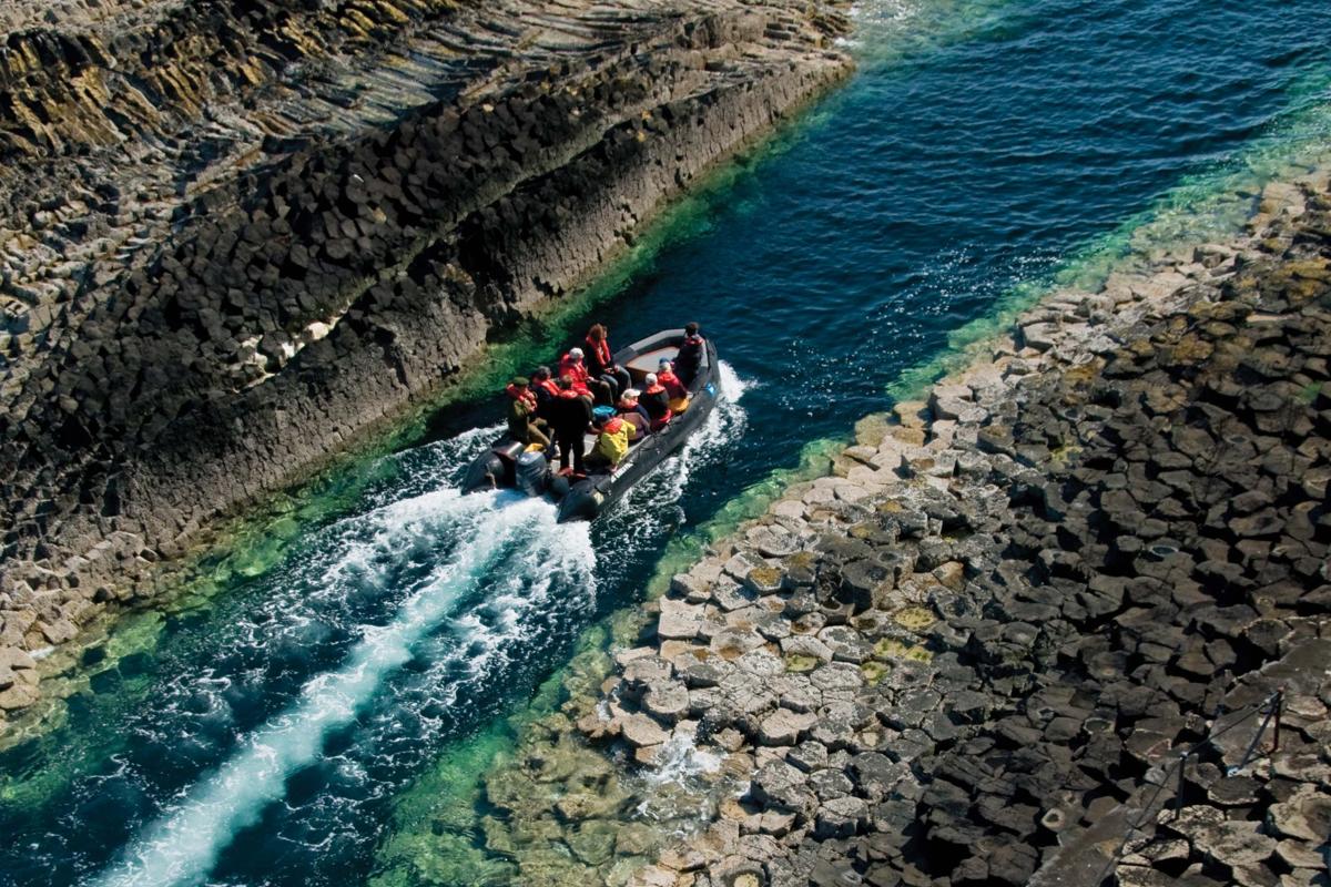 Guests enjoy zodiac exploration of the Basalt rock formations on the Island of Staffa in the Inner Hebrides of Scotland