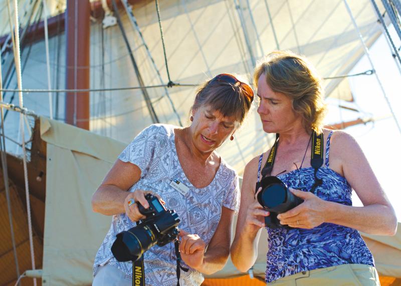 A guest receives photography tips from a  certified photo instructor on the ship Sea Cloud