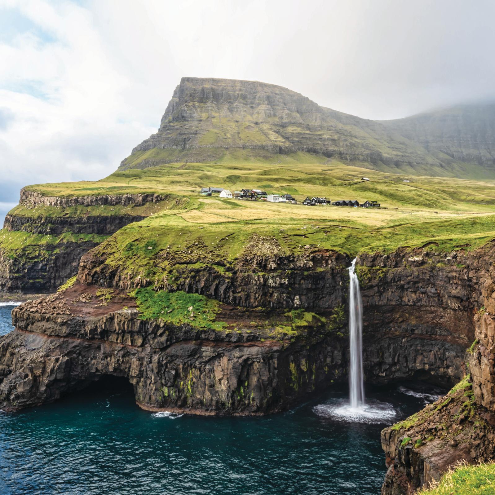 View of the iconic natural Mulafossur - Múlafossur Waterfall and Gasadalur village on Vágar Island, Faroe Islands, Denmark, Europe 