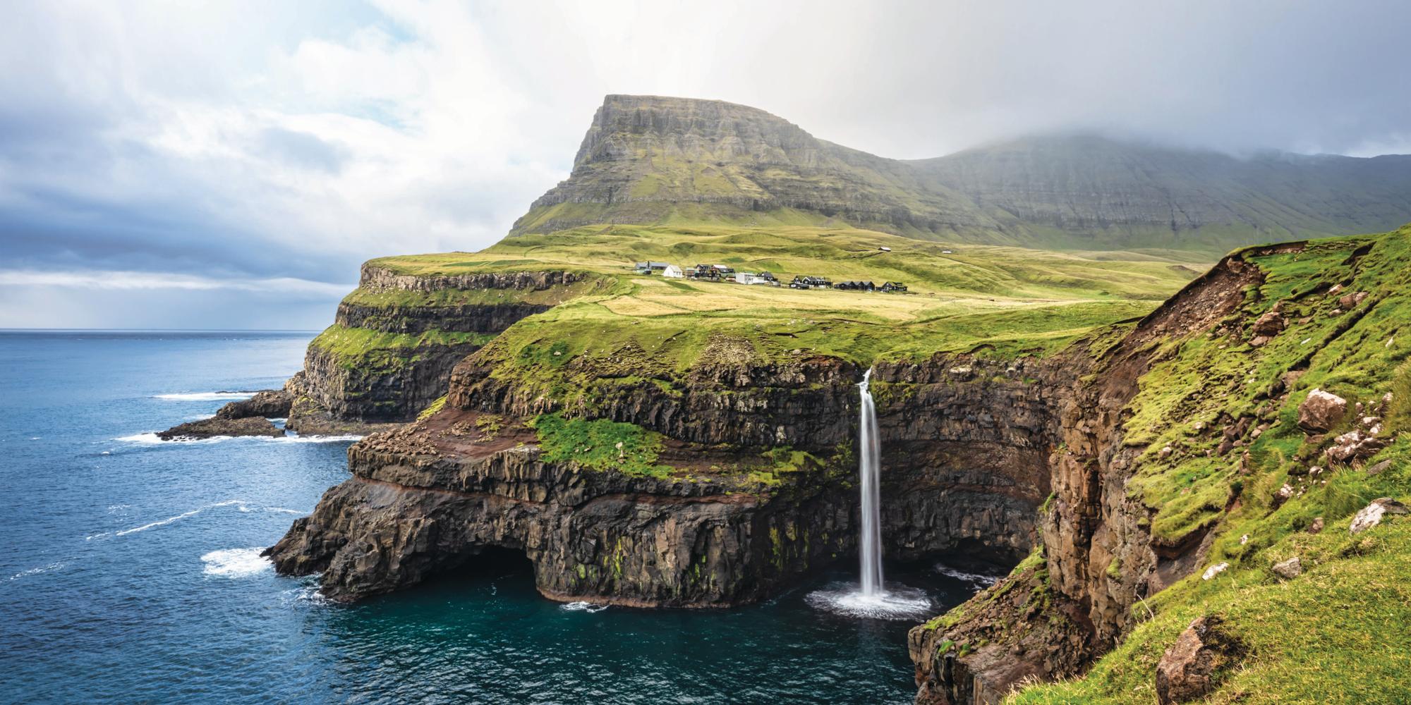 View of the iconic natural Mulafossur - Múlafossur Waterfall and Gasadalur village on Vágar Island, Faroe Islands, Denmark, Europe 