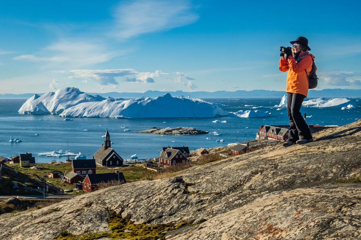 A guest photographs the view at the scenic viewpoint above the historic Zion Church, Ilulissat, Greenland