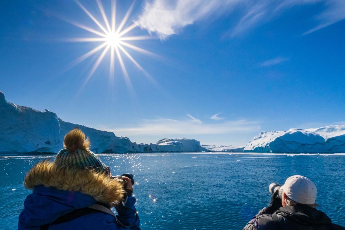 Guests photographing giant icebergs in Icefjord, Ilulissat, Greenland