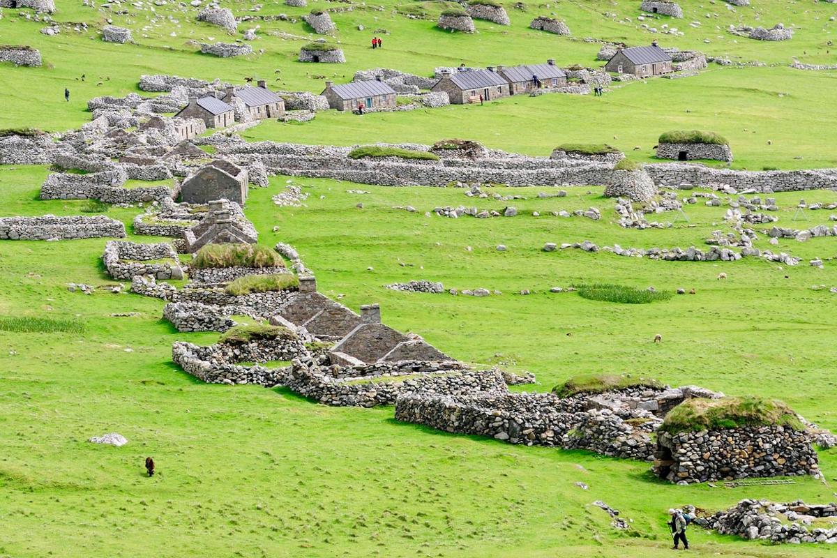 Guest exploring the main street of ruined cottages on Hirta, the main island of the St Kilda, archipelago, Scotland