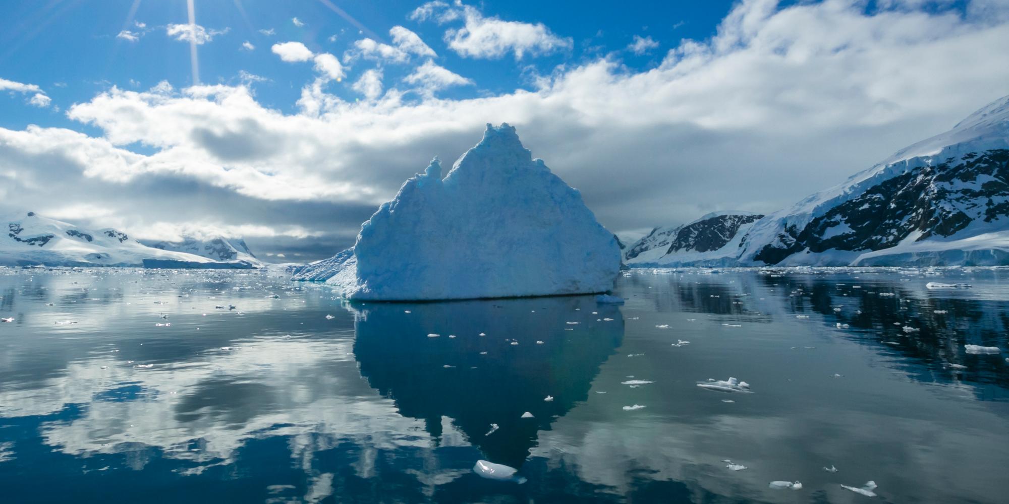 Blue Icebergs Reflections with Blue Sky and Sun Star, Neko Harbor, Antarctica.